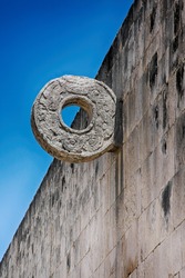 Chichen Itza - the wall of the Great Ball Court, high walls are rings carved by intertwined feathered snakes, beautiful blue sky.