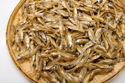 Close up of dried minnow fishes in bamboo basket on white background , Can be used as a background