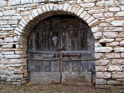 Old antique wooden door or gate. The door in the stone wall cracked.