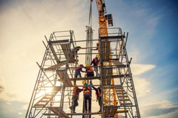 group of worker in safety uniform install reinforced steel column in construction site during sunset time