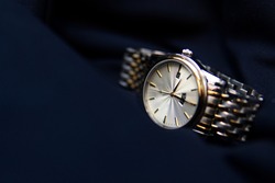 elegant gold watch on a navy blue background. Prestigious businessman watch on the background of a suit. Luxurious wrist watch with date.