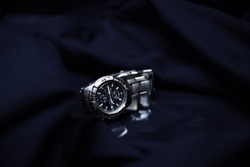 elegant sports chronograph on a bracelet. Stainless steel waterproof watch. A waterproof elegant watch in a dark scenery on a navy blue background.