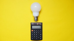 calculator and light bulb on yellow background. Concept showing the payment of electricity bills