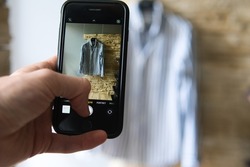 the man takes a picture of the shirt. Online sale of used clothes