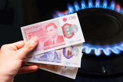 British pounds on the background of a gas stove. The energy crisis in Great Britain, gas shortages