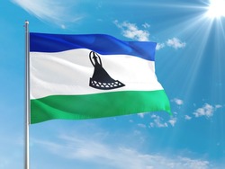 Lesotho national flag waving in the wind against deep blue sky. High quality fabric. International relations concept.