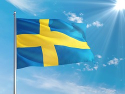 Sweden national flag waving in the wind against deep blue sky. High quality fabric. International relations concept.