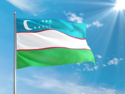 Uzbekistan national flag waving in the wind against deep blue sky. High quality fabric. International relations concept.