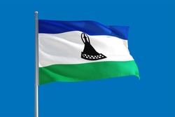 Lesotho national flag waving in the wind on a deep blue sky. High quality fabric. International relations concept.