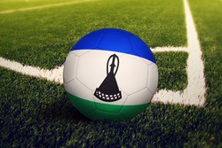 Lesotho flag on ball at corner kick position, soccer field background. National football theme on green grass.
