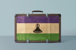 Lesotho flag on old vintage leather suitcase with national concept. Retro brown luggage with copy space text.