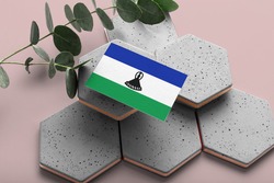 Lesotho flag on hexagon stylish stones. Pink copy space background. Flat lay, top view minimal national concept.