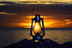 oil lamp on the beach at sunrise .