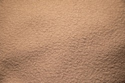 Beige fleecy fabric texture. Small curls, similar to wool or skin like astrakhan fur. Warm and soft textiles for clothing and handicrafts. Background image for website, book, postcard.
