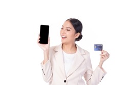 Portrait Asian happy young girl wearing pink suit happy smile and showing plastic credit card while holding mobile phone isolated on white background. Business online shopping concept.