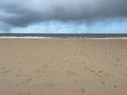 Landscape of sea stormy rain clouds over ocean from sandy beach with beautiful moody grey sky drip on blue in Gorleston near Great Yarmouth in Norfolk East Anglia UK on holiday on Spring cold day walk