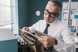 Corporate businessman searching for paperwork in the filing cabinet