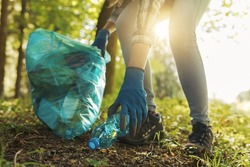 Cleanup volunteer collecting trash in the forest and holding a garbage bag, environmental protection concept