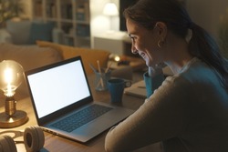 Young woman sitting at desk and connecting with her laptop at home, technology and communication concept