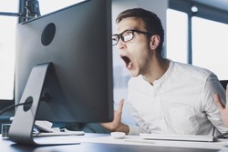 Angry office worker sitting at desk and shouting at the computer, system failure concept