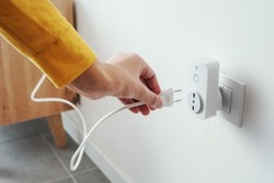Woman plugging a device into a smart plug, virtual assistant and domotics concept