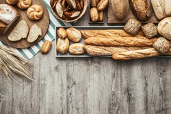 Freshly baked delicious bread on a rustic wooden worktop with copy space, healthy eating concept, flat lay