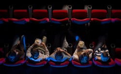 Young people sitting at the cinema, watching a movie and eating pop corn, top view