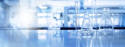 shadow of scientist and glass flask and cylinder equipment in medical science lab blue banner background