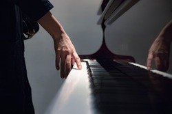 a girl standing next to an old classic piano touching the keys with her hand, a girl playing the piano close up blurred