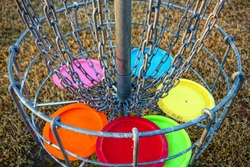 Disc golf basket with discs. The discs are in focus.