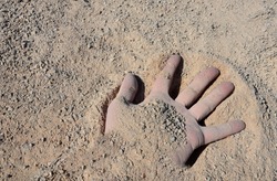 a man's hand buried in an accident that brings earthquakes or mining accidents. in fine gravel which is used for park construction of roads. fingers covered with sand in a pile dumped by a truck