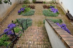 metal gate with decorative fittings in the arch garden with flowers in the yard which is entered by brick steps down. monastery garden with paths in the shape of a cross, square. surrounded by a wall