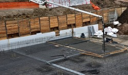 concreting the floor of underground garages with the help of a mixer and a pump with a hose. concrete reinforcement wires are entwined in a gray mesh. monolithic constructions of large buildings