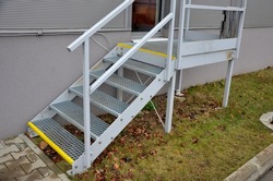 industrial hall, warehouse has a side door at a steep staircase with high resistance even under heavy load galvanized steel floor grate and railings. expanded metal, edges of stairs of safety yellow 
