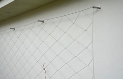 metal trellises made of interconnected stainless steel cables attached to the wall of the house grow and wrap the vine. column tunnel. detail of mesh clamps, grip, holder