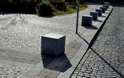 stone cubes barriers as protection of a nice lawn cube cubes on a paved sidewalk platform of a tram protected from the entry of cars 