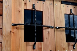 The wooden cabin is made of wooden construction. on the window there is a black metal grill in the shape of a cross. door secured with a wrought-iron grid against robbery and burglary. the thief will 