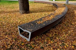 wooden benches by the lawn. wood paneled entice you to sit down. therapeutic walks in the castle park. metal frame with a slightly heart-shaped round long seat, autumn leaf color, covered