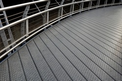 staircase and wide pedestrian bridge with perforated metal floor. galvanized sheet metal with circular holes. white railings like on a ship in the arch. handrail made of polished stainless steel pipe.