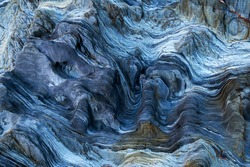 Detail of a rock with variants of blue. Rock full of curves and smooth cuts resulting from the erosive effect of sea. Close up rocks, texture dramatic and colorful erosional water formation. Stone