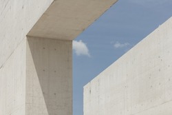Architectural photography. Geometric composition with two large and strong cement blocks. building against the blue sky with white clouds. Modern structures architecture. Minimalist design fragments.