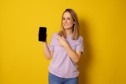Trendy Mobile Phone. Portrait of cheerful young woman holding cellphone with black blank screen in hand, showing device.