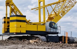 Crawler crane on a construction site with focus on the machine deck, counterweight and treads.
