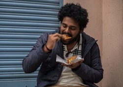 Young mans enjoying eat south Indian food in chats street, wearing face mask . 