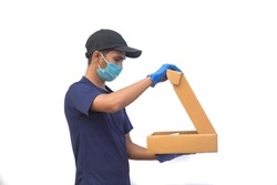 Delivery, shipping and postal service concept. Delivery man opening the cardboard box with safety precautions wearing face surgical mask and hand gloves to avoid contact with the customer.Isolated 