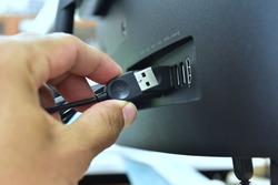 Unplugging USB cable from computer. Disconnect USB cord from the computer. Man hold USB plug against computer.