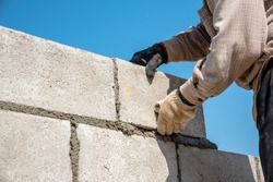 masonry worker make concrete wall by cement block and plaster at construction site 