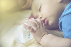 closeup newborn  Baby hand and finger  holding bottle while sleeping and drinking milk 