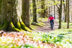 Woman cycling on trail in forest