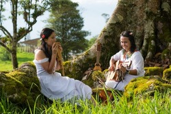 indigenous women with instruments singing in nature
